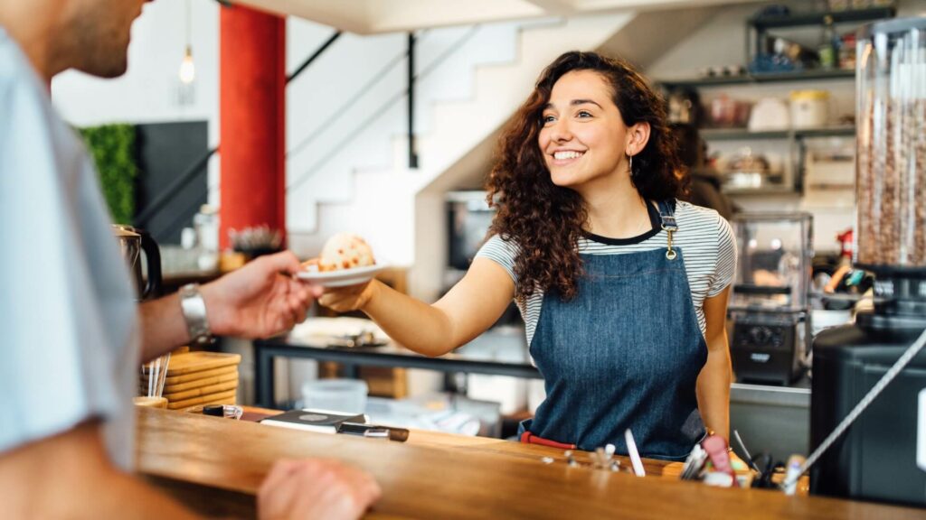 Eine Barista begrüßt einen Kunden im Café