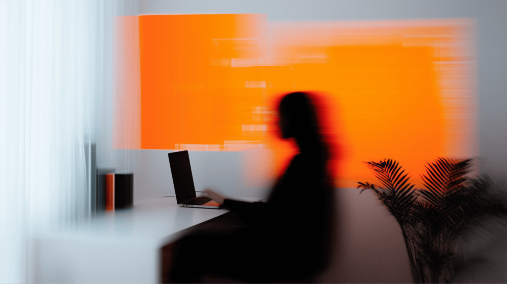 Foto von Person an Arbeitsplatz im Homeoffice mit Laptop mit orangem Motion-Blur Effekt. 