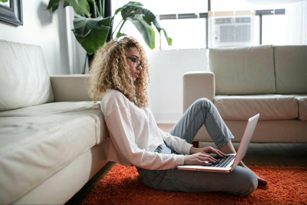 Dame sitzt mit Laptop an einer Couch